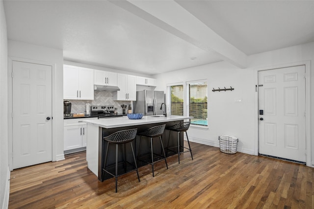 3404 Rosedale St, Houston, TX 77004 - kitchen featuring stainless steel appliances, tasteful backsplash, a kitchen bar, a kitchen island with sink, and dark wood-style floors
