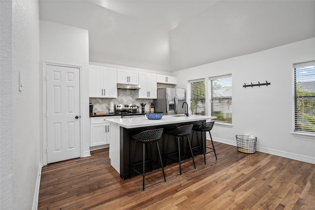 3404 Rosedale St, Houston, TX 77004 - kitchen with appliances with stainless steel finishes, under cabinet range hood, an island with sink, a breakfast bar, and white cabinetry