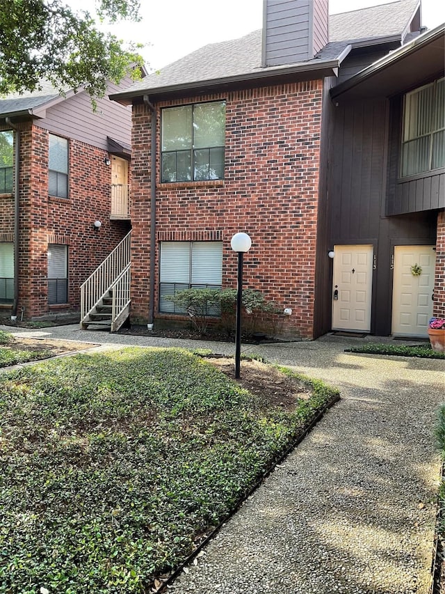 3100 Walnut Bend Ln Unit 113, Houston, TX 77042 - doorway to property with a chimney, brick siding, and a shingled roof