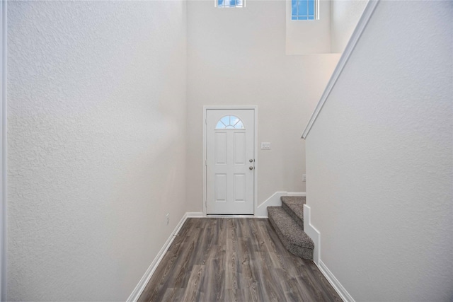 16853 Needlepoint Dr, Conroe, TX 77302 - doorway with stairs, dark wood finished floors, a textured wall, and a high ceiling