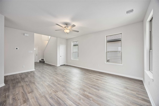 16853 Needlepoint Dr, Conroe, TX 77302 - unfurnished living room with ceiling fan, wood finished floors, and stairway