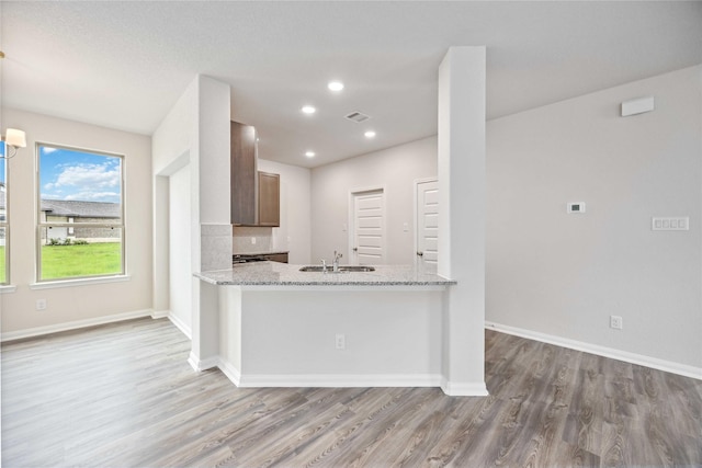 16853 Needlepoint Dr, Conroe, TX 77302 - kitchen featuring wood finished floors, recessed lighting, light stone countertops, and a peninsula