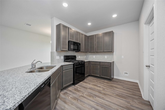 16853 Needlepoint Dr, Conroe, TX 77302 - kitchen with black appliances, light stone countertops, light wood-type flooring, backsplash, and recessed lighting