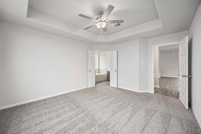 16853 Needlepoint Dr, Conroe, TX 77302 - unfurnished bedroom with a raised ceiling, carpet floors, connected bathroom, and ceiling fan