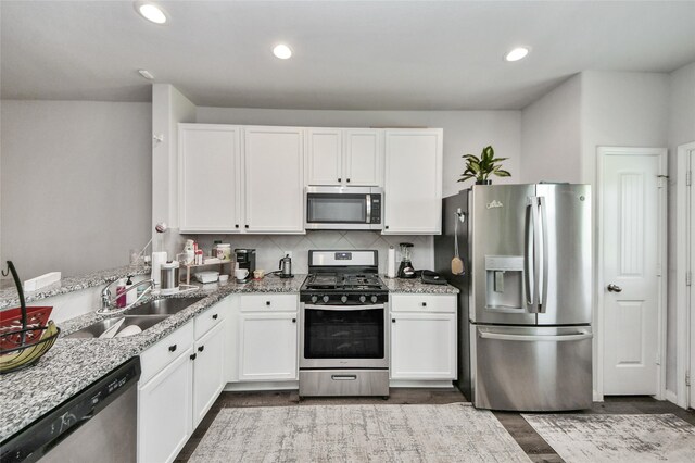 3923 Calasso Ct, Katy, TX 77493 - kitchen with stainless steel appliances, white cabinetry, dark wood-style flooring, light stone counters, and backsplash