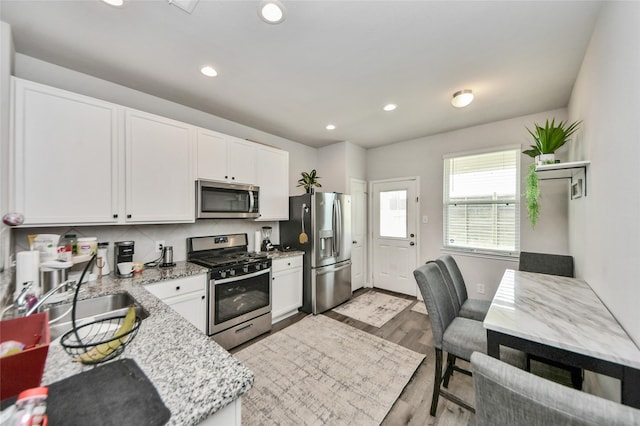 3923 Calasso Ct, Katy, TX 77493 - kitchen with stainless steel appliances, light stone counters, white cabinetry, recessed lighting, and light wood-type flooring