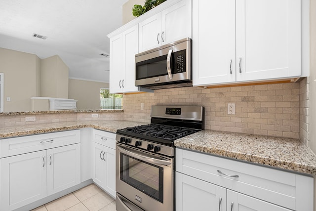 17130 Mountain Crest Dr, Spring, TX 77379 - kitchen featuring appliances with stainless steel finishes, decorative backsplash, light stone counters, and white cabinetry