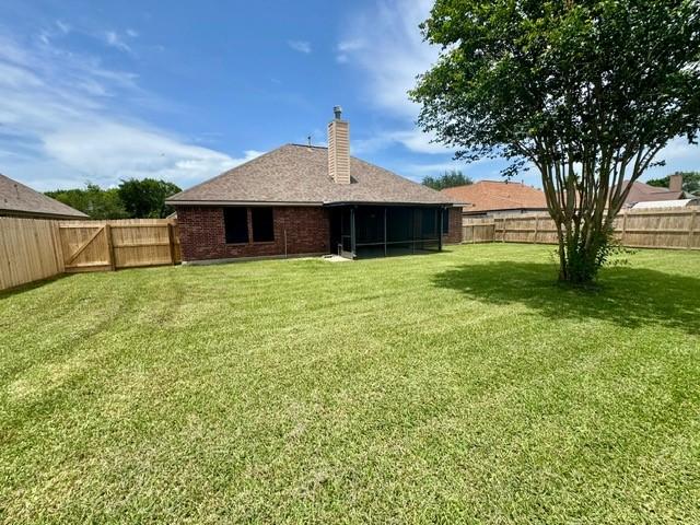 108 Audubon Woods Dr, Richwood, TX 77531 - rear view of house with a fenced backyard, a sunroom, a chimney, and brick siding