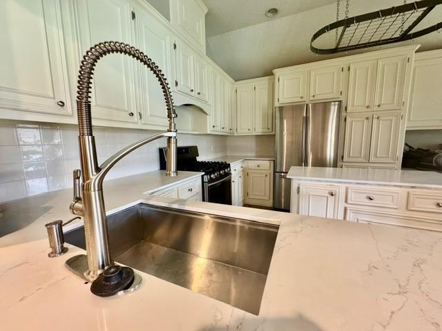 108 Audubon Woods Dr, Richwood, TX 77531 - kitchen featuring gas range, freestanding refrigerator, tasteful backsplash, light stone counters, and lofted ceiling