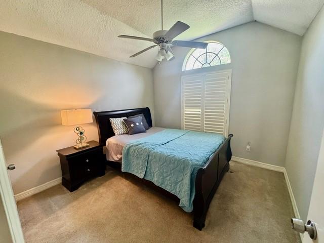 108 Audubon Woods Dr, Richwood, TX 77531 - bedroom featuring vaulted ceiling, a textured ceiling, a ceiling fan, and carpet flooring