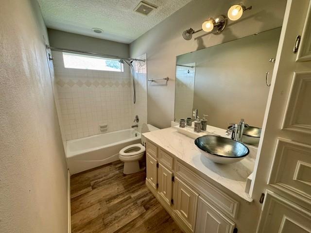 108 Audubon Woods Dr, Richwood, TX 77531 - full bathroom featuring wood finished floors, vanity, shower / tub combination, and a textured ceiling