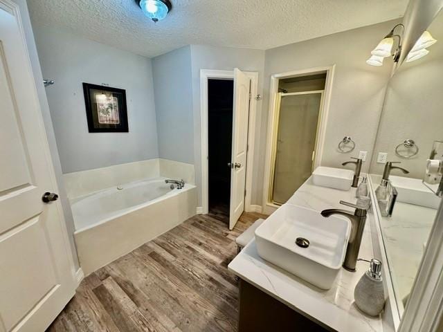 108 Audubon Woods Dr, Richwood, TX 77531 - full bath with wood finished floors, a bath, a stall shower, a textured ceiling, and double vanity