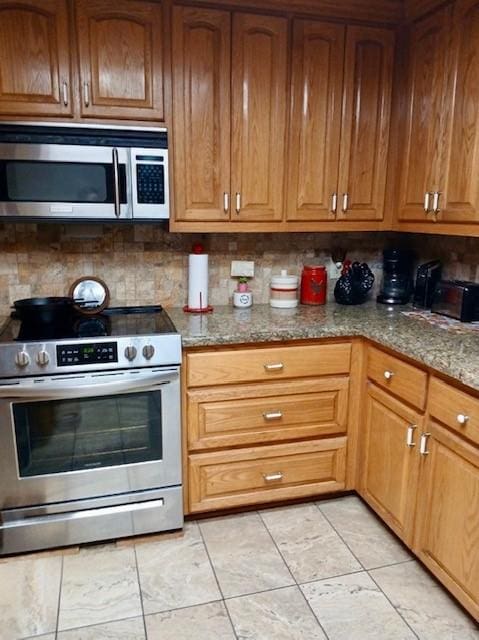 903 Happy Holw, Sweeny, TX 77480 - kitchen featuring stainless steel appliances, stone counters, brown cabinets, and tasteful backsplash