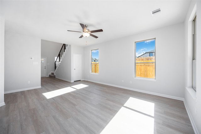 16866 Needlepoint Dr, Conroe, TX 77302 - unfurnished living room featuring a ceiling fan, healthy amount of natural light, stairs, and wood finished floors