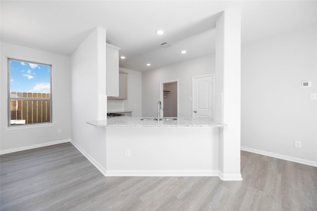 16866 Needlepoint Dr, Conroe, TX 77302 - kitchen with light wood finished floors, light stone counters, recessed lighting, a peninsula, and white cabinets