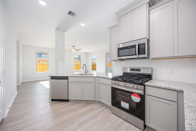 16866 Needlepoint Dr, Conroe, TX 77302 - kitchen with stainless steel appliances, a peninsula, a ceiling fan, light wood finished floors, and recessed lighting
