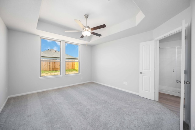 16866 Needlepoint Dr, Conroe, TX 77302 - unfurnished bedroom with a tray ceiling, carpet, and ceiling fan