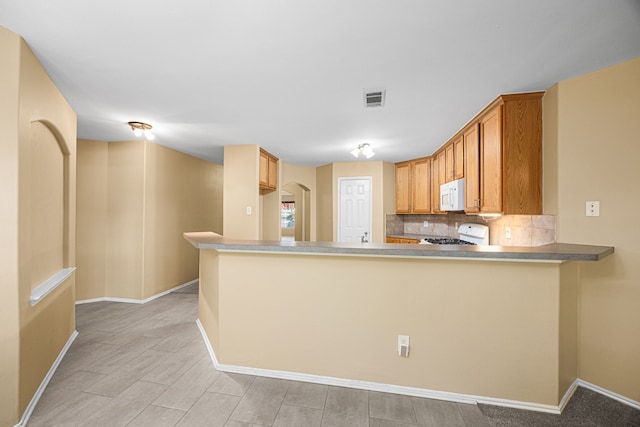 14319 Heron Marsh Dr, Cypress, TX 77429 - kitchen with white microwave, stove, a peninsula, tasteful backsplash, and light wood finished floors