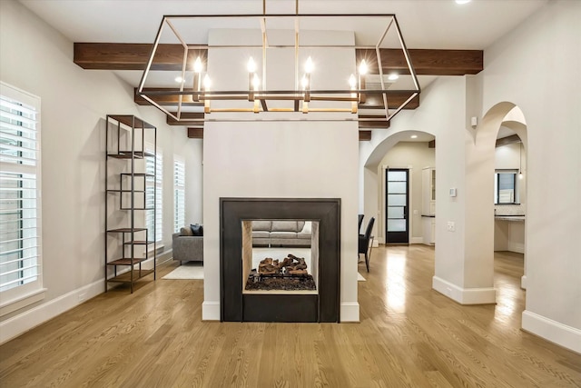 1116 W Drew St, Houston, TX 77006 - unfurnished living room featuring a chandelier, beam ceiling, arched walkways, and wood finished floors