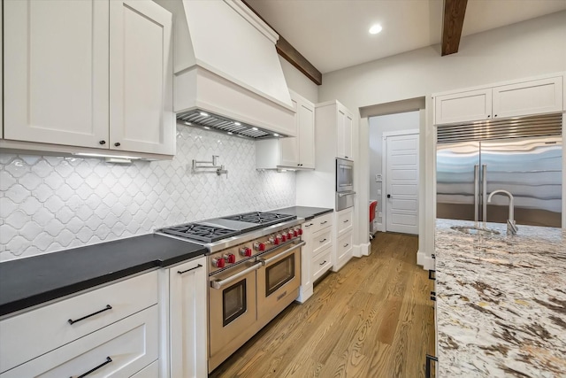 1116 W Drew St, Houston, TX 77006 - kitchen with premium appliances, custom range hood, light wood finished floors, white cabinets, and a warming drawer