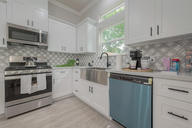 7108 Saint Augustine St, Houston, TX 77021 - kitchen with stainless steel appliances, crown molding, light countertops, white cabinetry, and decorative backsplash