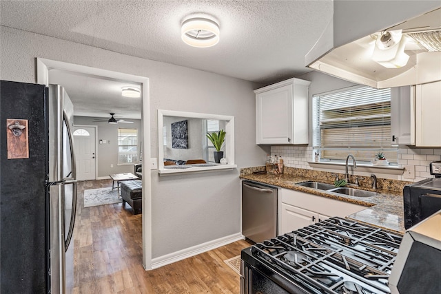 3318 Europa St, Houston, TX 77022 - kitchen featuring appliances with stainless steel finishes, tasteful backsplash, white cabinetry, light wood-style flooring, and a textured ceiling