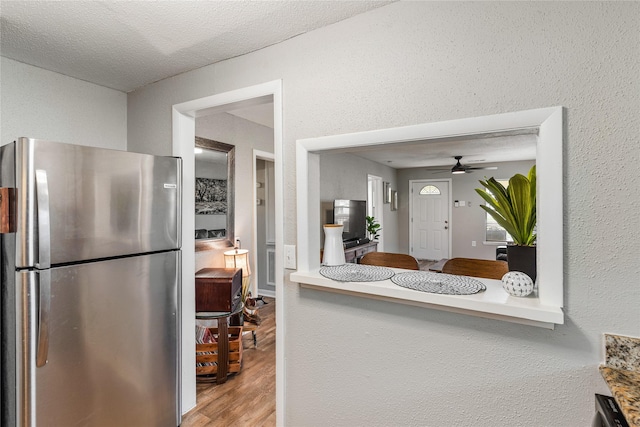 3318 Europa St, Houston, TX 77022 - kitchen with freestanding refrigerator, ceiling fan, wood finished floors, and a textured wall