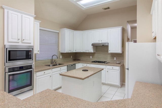 14510 Kings Head Dr, Houston, TX 77044 - kitchen featuring stainless steel appliances, under cabinet range hood, backsplash, white cabinets, and lofted ceiling