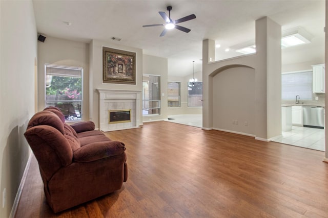 14510 Kings Head Dr, Houston, TX 77044 - living room featuring light wood finished floors, a ceiling fan, a tiled fireplace, and a chandelier