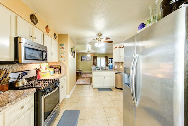 11734 Filaree Trl, Houston, TX 77044 - kitchen featuring stainless steel appliances, decorative backsplash, light tile patterned flooring, a ceiling fan, and white cabinets