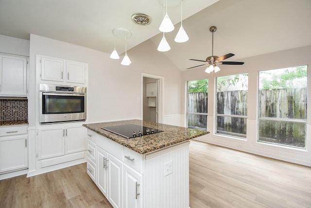 1010 Rock Canyon Dr, Katy, TX 77450 - kitchen featuring oven, black electric cooktop, light wood-style floors, dark stone counters, and white cabinetry