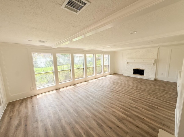 16627 Aldenham Pl, Spring, TX 77379 - unfurnished living room featuring a textured ceiling, wood finished floors, crown molding, a fireplace, and a decorative wall