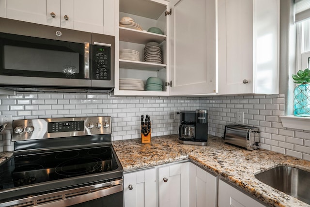18607 Warrior Rd, Galveston, TX 77554 - kitchen featuring electric range, white cabinets, tasteful backsplash, open shelves, and light stone counters