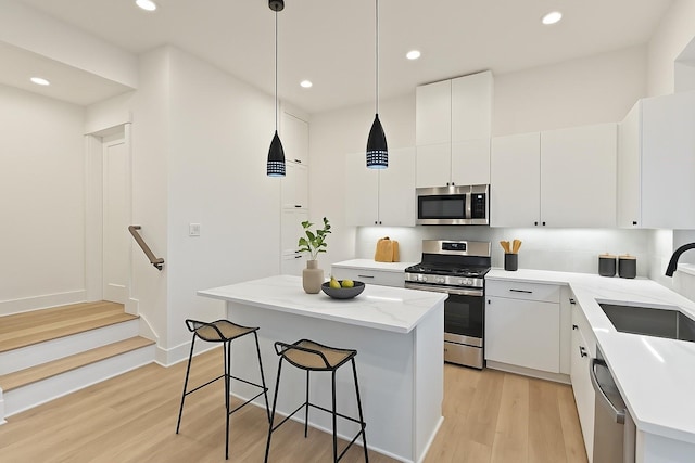 1604 Mary St, Houston, TX 77026 - kitchen with appliances with stainless steel finishes, a kitchen breakfast bar, a kitchen island, light wood-style floors, and recessed lighting