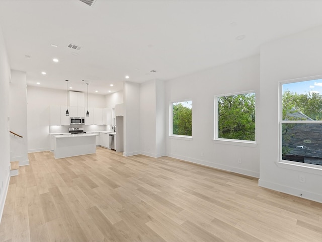 1604 Mary St, Houston, TX 77026 - unfurnished living room featuring plenty of natural light, light wood-style flooring, recessed lighting, and stairway