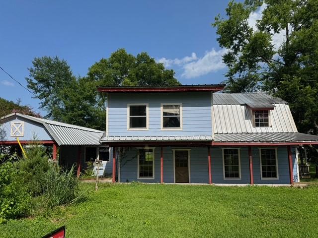 771 Governor Wood Dr, Point Blank, TX 77364 - back of property with a lawn, a metal roof, and covered porch