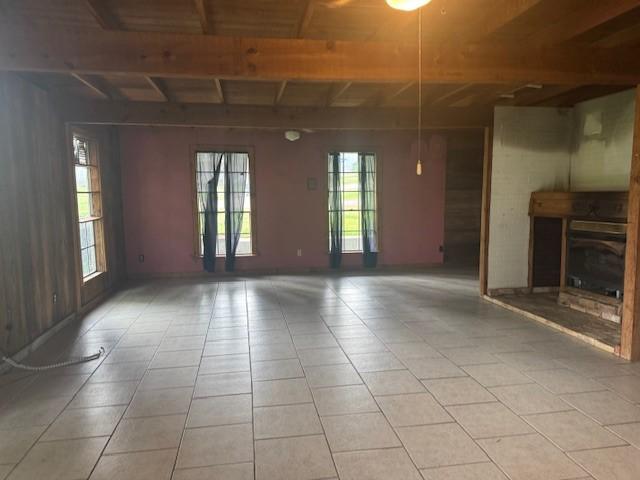 771 Governor Wood Dr, Point Blank, TX 77364 - unfurnished living room featuring light tile patterned floors, a glass covered fireplace, and beamed ceiling