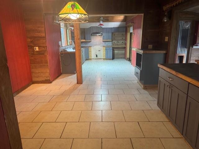 771 Governor Wood Dr, Point Blank, TX 77364 - kitchen with wooden walls, gray cabinetry, under cabinet range hood, and pendant lighting