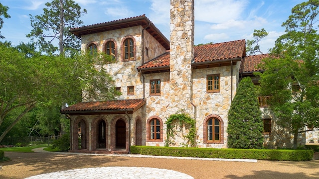 603 W Friar Tuck Ln, Houston, TX 77024 - view of front of property with stone siding, a tile roof, and a chimney