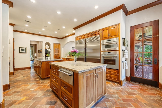 603 W Friar Tuck Ln, Houston, TX 77024 - kitchen featuring a warming drawer, built in refrigerator, a center island with sink, crown molding, and brown cabinetry