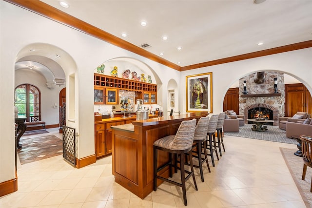 603 W Friar Tuck Ln, Houston, TX 77024 - indoor wet bar with crown molding, recessed lighting, a stone fireplace, arched walkways, and light tile patterned floors