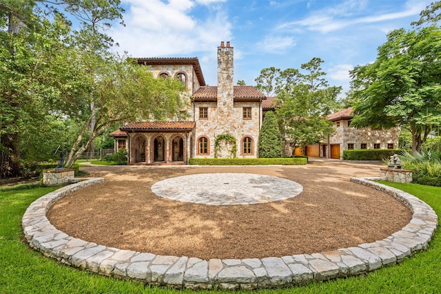 603 W Friar Tuck Ln, Houston, TX 77024 - rear view of property featuring stone siding, a tiled roof, a chimney, and curved driveway