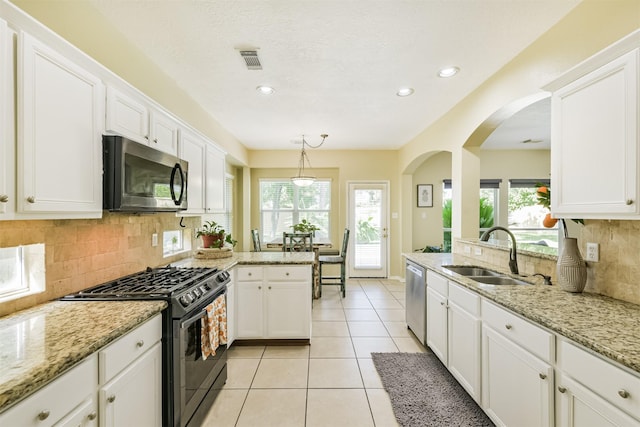 227 Fairwind Trail Dr, The Woodlands, TX 77385 - kitchen featuring appliances with stainless steel finishes, a peninsula, arched walkways, white cabinets, and recessed lighting