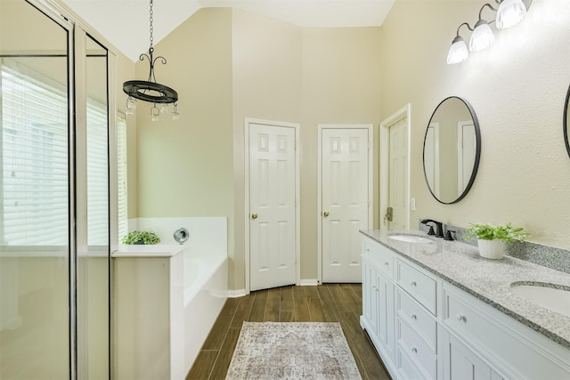 227 Fairwind Trail Dr, The Woodlands, TX 77385 - full bathroom with double vanity, wood finished floors, a garden tub, and vaulted ceiling