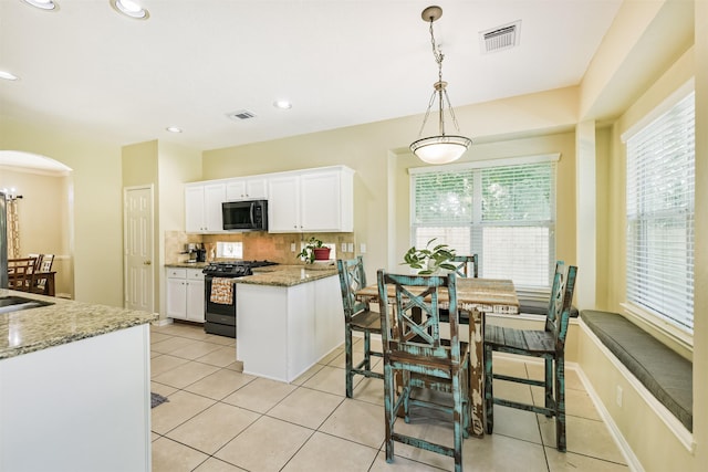 227 Fairwind Trail Dr, The Woodlands, TX 77385 - kitchen with black appliances, white cabinetry, backsplash, arched walkways, and light tile patterned flooring
