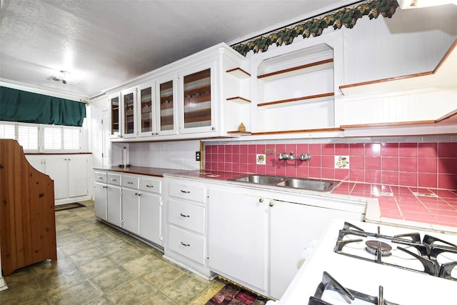 3614 Billingsley St, Houston, TX 77009 - kitchen with stainless steel countertops, backsplash, white cabinets, and glass insert cabinets