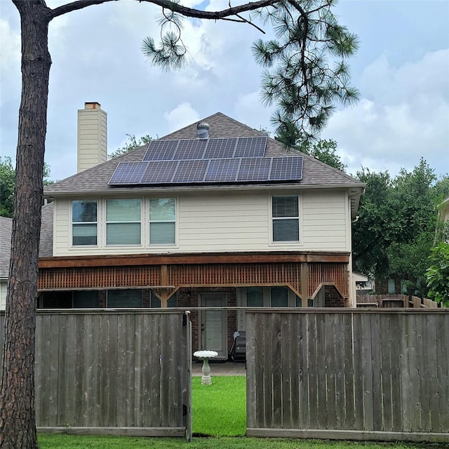 110 Greenridge Cir, League City, TX 77573 - rear view of property featuring solar panels, a chimney, and roof with shingles