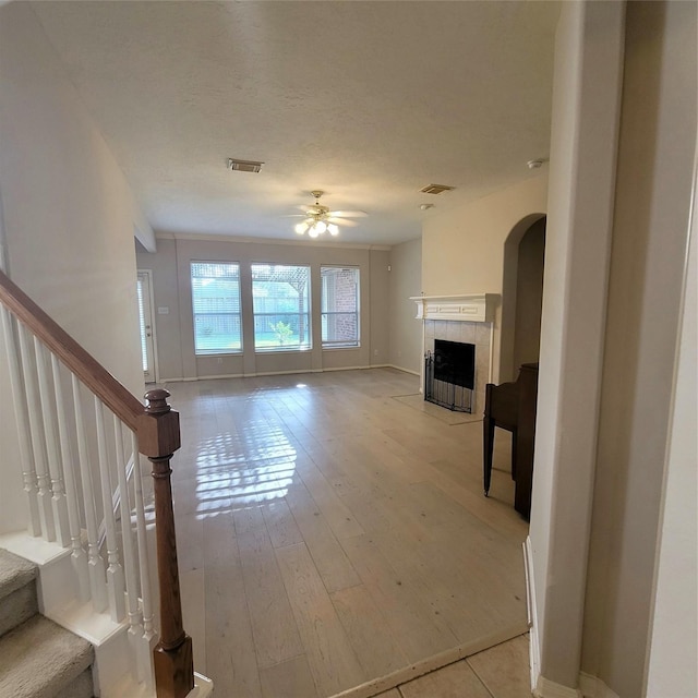 110 Greenridge Cir, League City, TX 77573 - unfurnished living room with ceiling fan, stairs, a fireplace, light wood-style flooring, and arched walkways