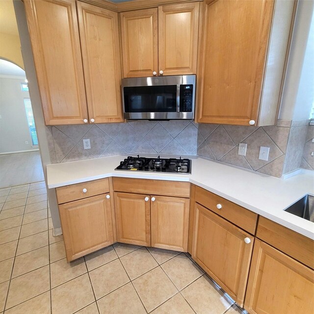 110 Greenridge Cir, League City, TX 77573 - kitchen with stainless steel microwave, gas cooktop, arched walkways, light tile patterned floors, and decorative backsplash