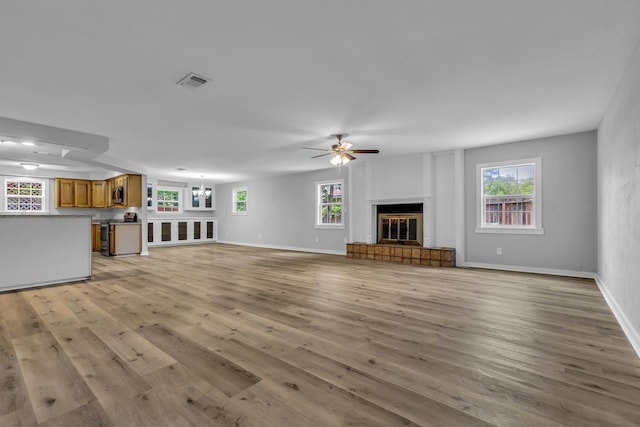 10650 Forest Creek Dr, Conroe, TX 77318 - unfurnished living room with light wood-style flooring, a ceiling fan, and a glass covered fireplace